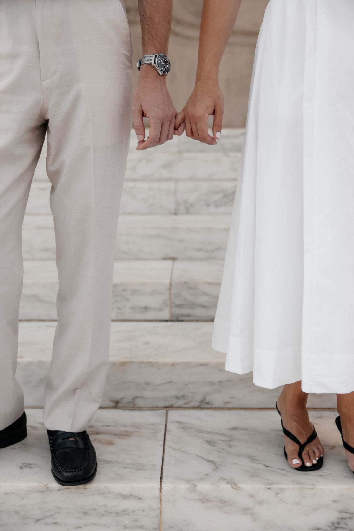 Close-up of Joseph and Filiz linking pinkies on the marble steps